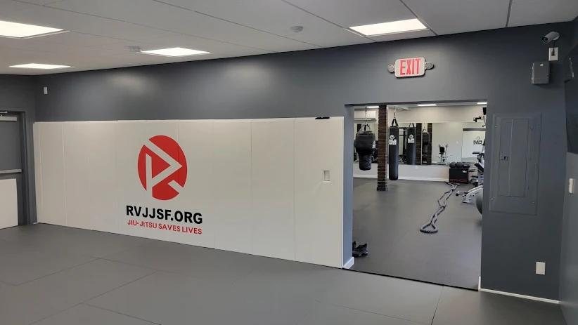The scholarship wall in the mat room, opening into the gym